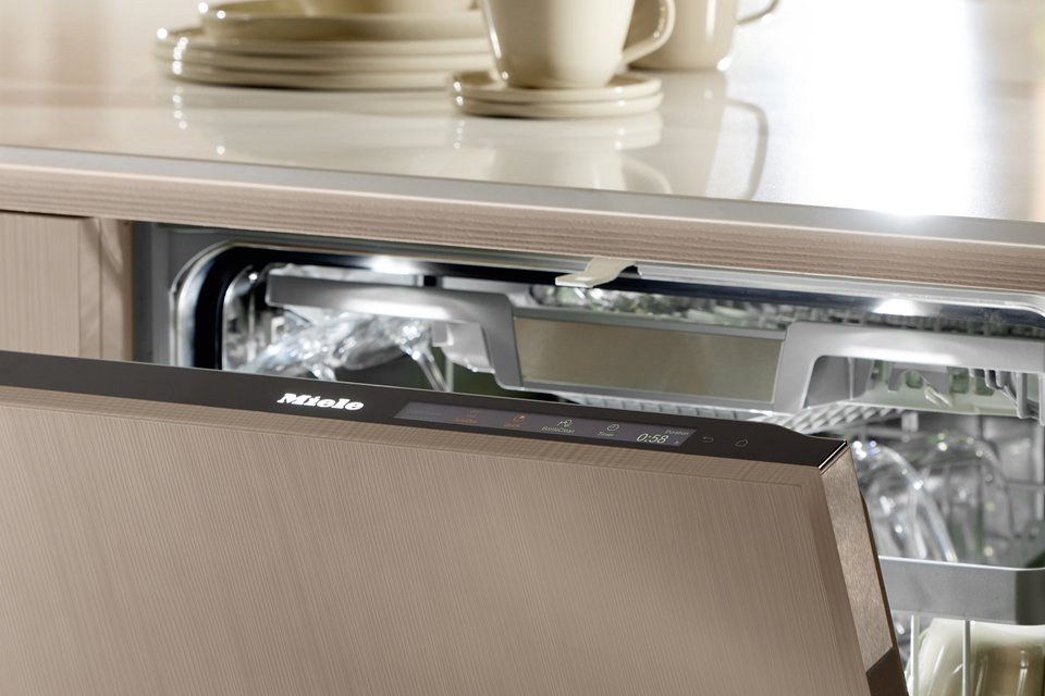 Close up top shot of Miele dishwasher with door slightly ajar and watering filtering inside.